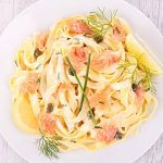 Tagliatelle met gerookte zalm in romige roomsaus met citroen, kappertjes, bieslook en dille.